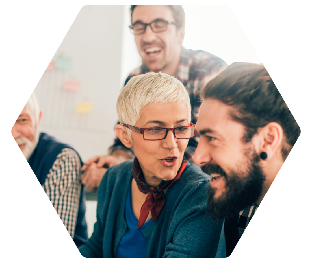 Mehrere Personen unterschiedlichen Alters reden und lachen zusammen vor einem Flipchart.